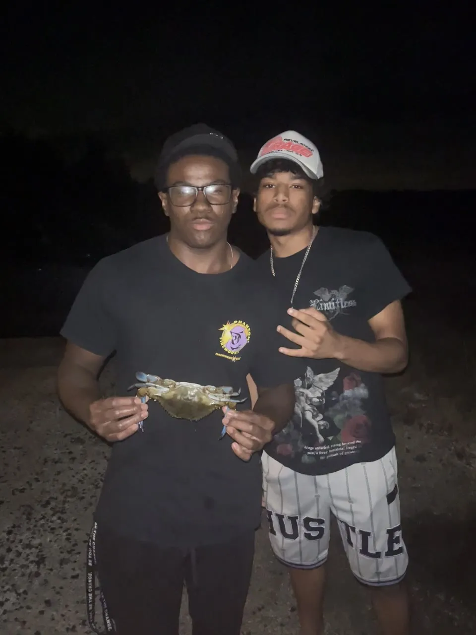Theodore and a friend holding up a blue crab at night
